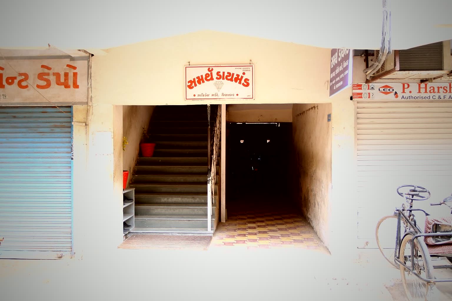 The street entrance of the original Samarth Diamond unit in Visnagar, its hand-painted Gujarati signboard above the stairway up to the workshop.