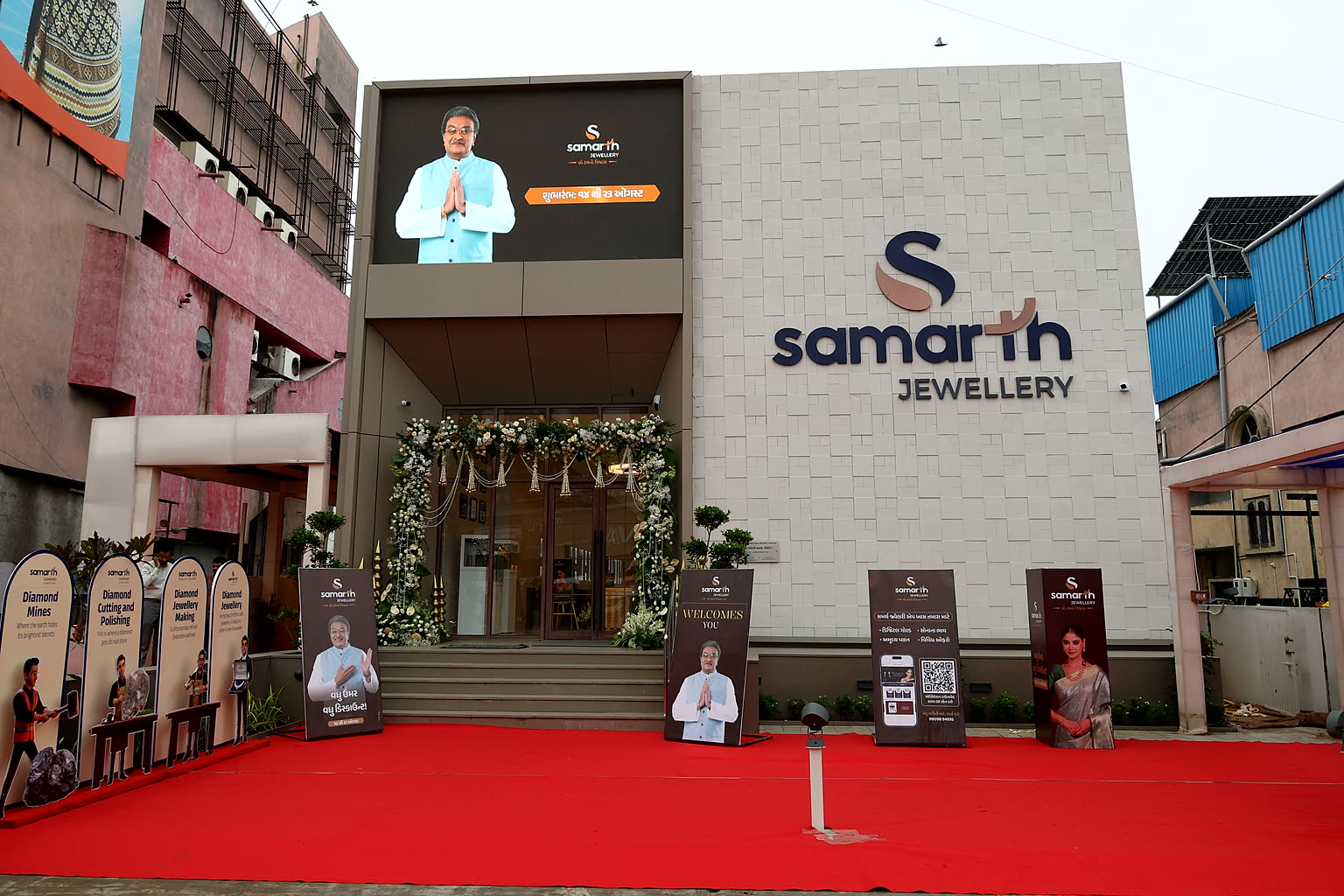The Anand showroom on its opening day, the Samarth Jewellery sign on the stone façade above a garlanded entrance.